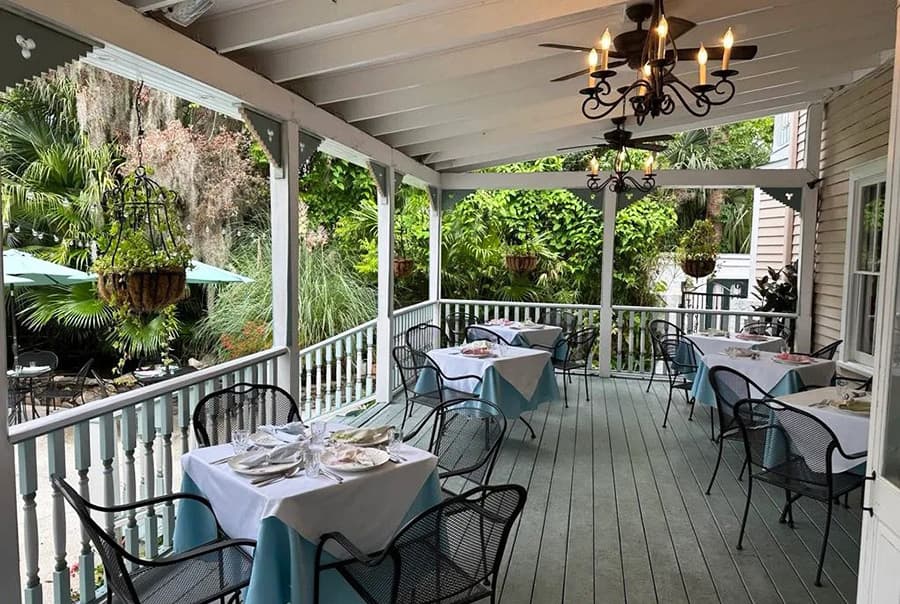 A cozy outdoor dining area with tables set for meals, surrounded by greenery.